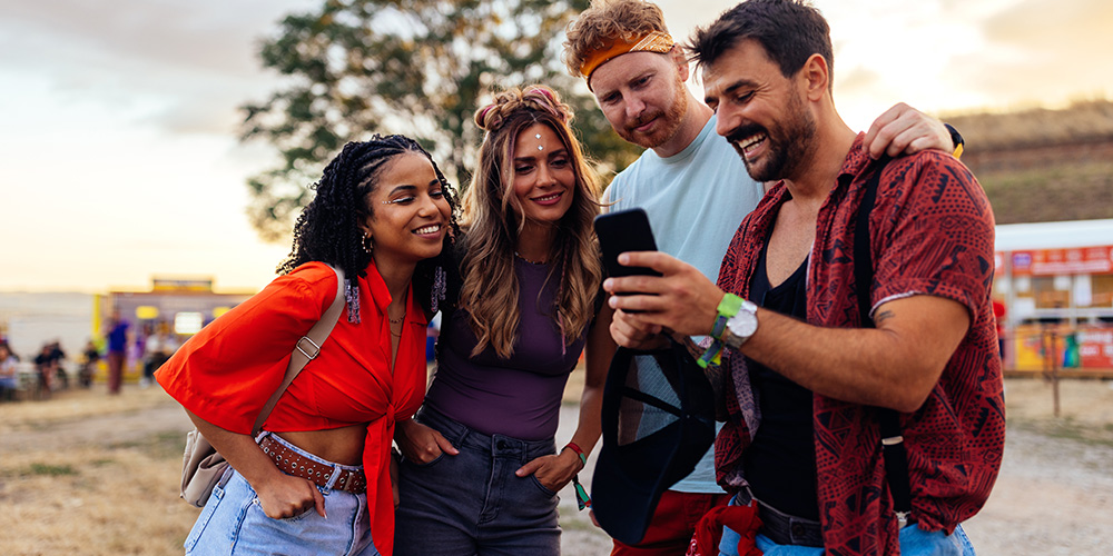 Group of friends at a festival looking at a phone
