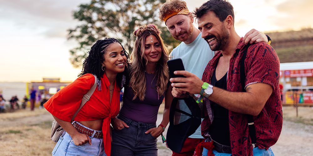 Group of friends at a festival looking at a phone