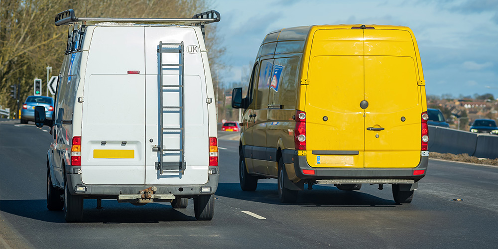 a yellow van and a white van driving next to each other