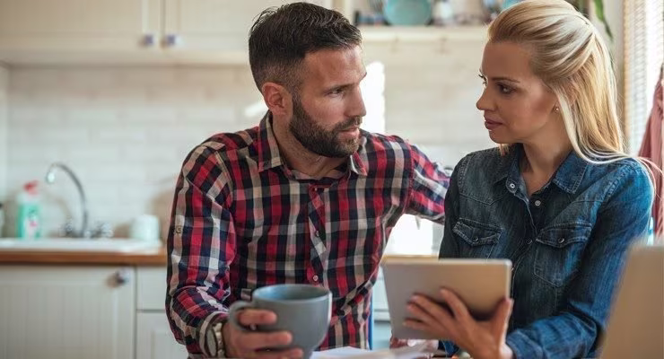 Couple discussing finances, looking at tablet