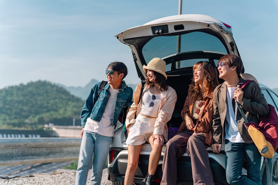 Group of friends stood by car on beach