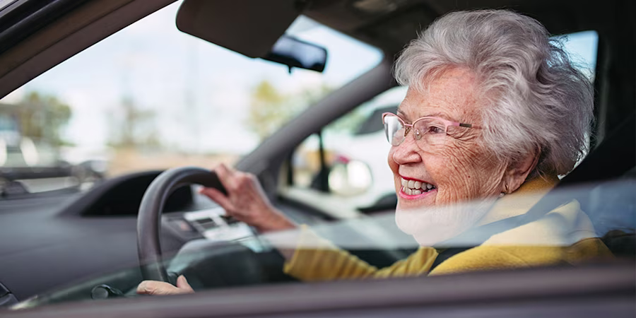 smiling older woman driving car