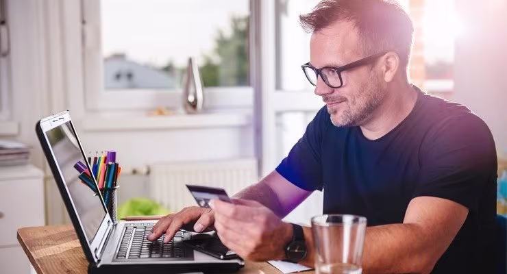 Man using credit card to pay via a laptop