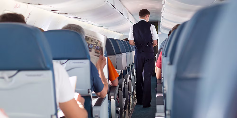 Air steward walking down aeroplane aisle