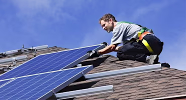 A person installing solar panels on the roof of a house