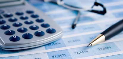 calculator, pen and glasses on paperwork with data on