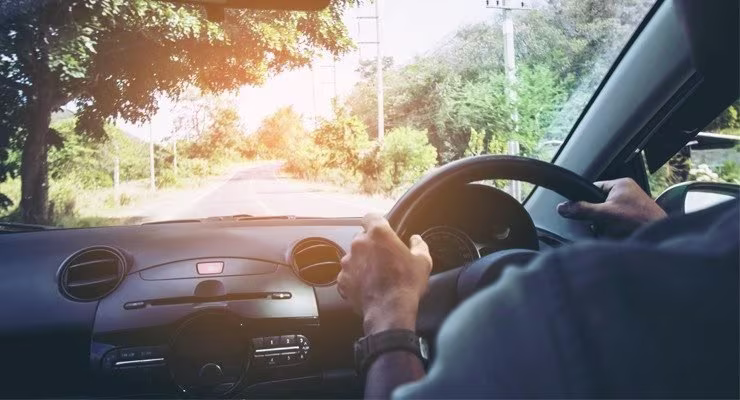 Man driving car sunny road