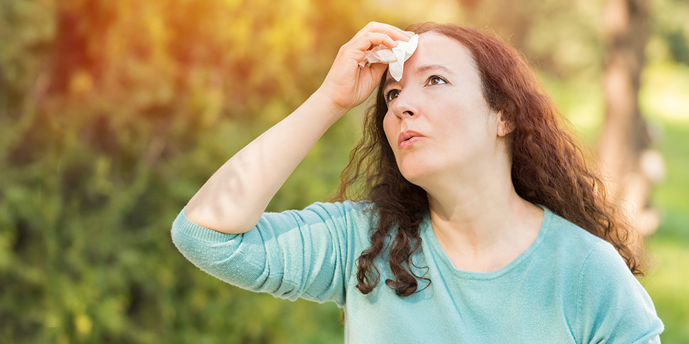 woman wiping sweat from forehead