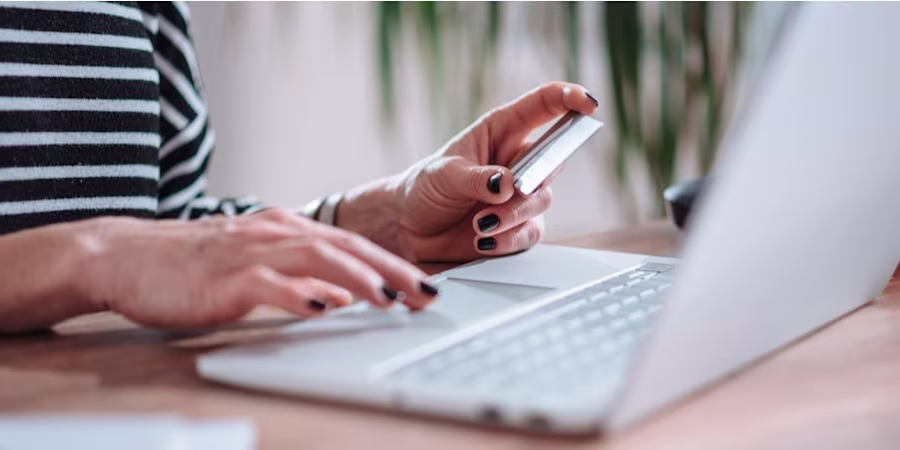 hands holding credit card at laptop