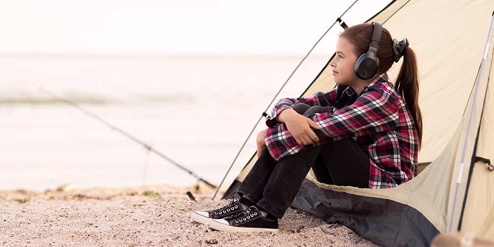 young girl wearing headphones sitting in a tent