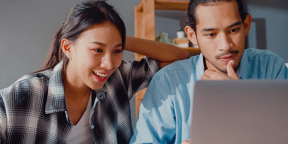 young couple looking at computer happy