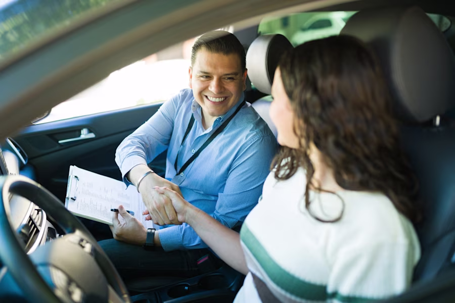 Driving instructor shaking hands with female driver