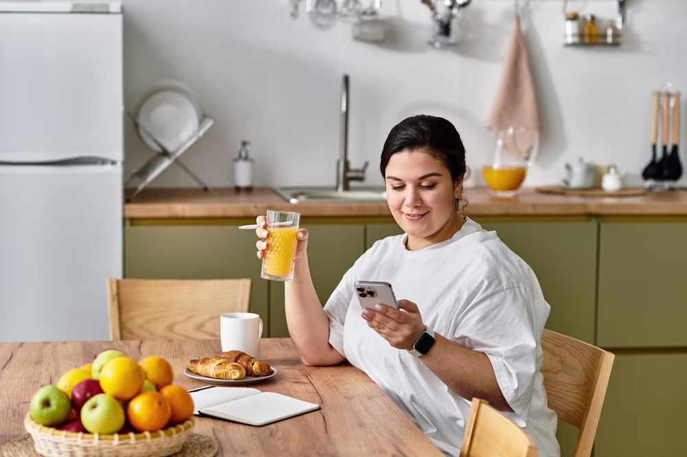 Woman on phone eating breakfast
