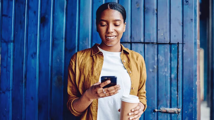 Woman using mobile phone against a painted blue wall