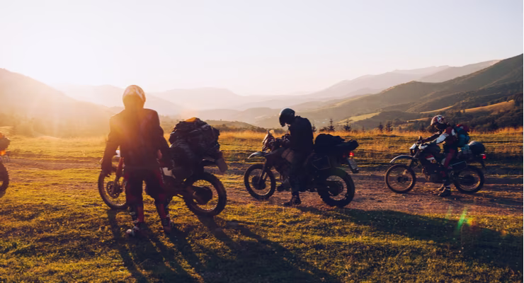 Man on motorbike top of hill at sunrise