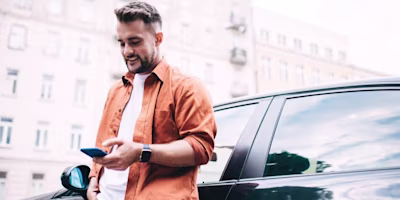 Driver leaning against his car