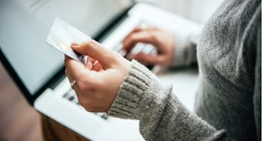 Woman on laptop with MoneySuperMarket logo displayed