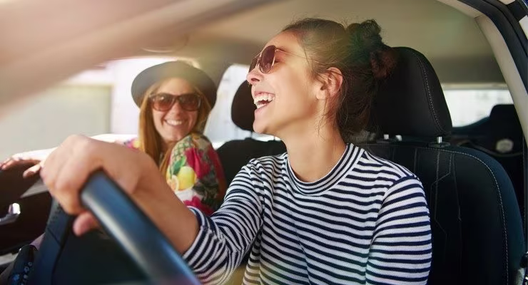 Young female driver driving a car with a female passenger