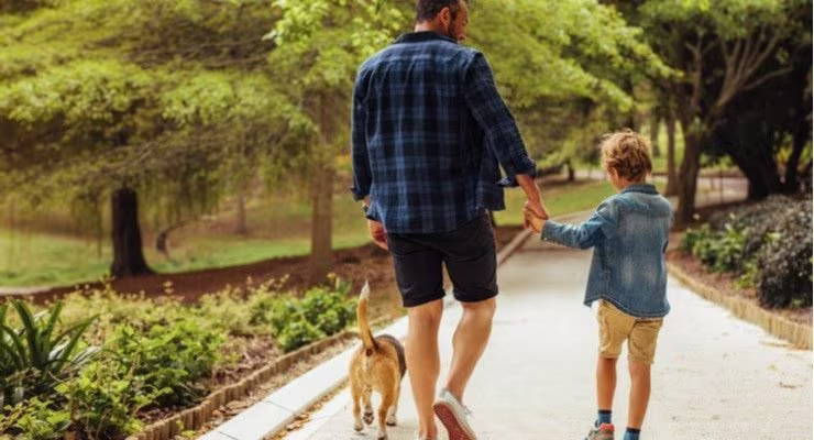 Man and child walking dog in forest
