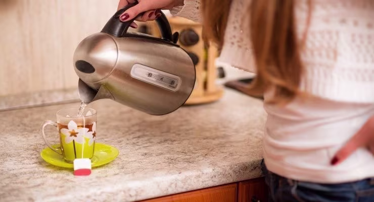 Woman pouring drink into cup using kettle