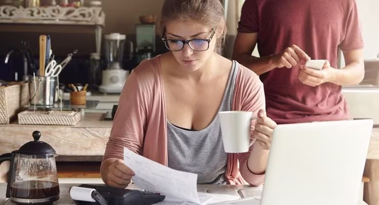 Woman looking at bills in kitchen