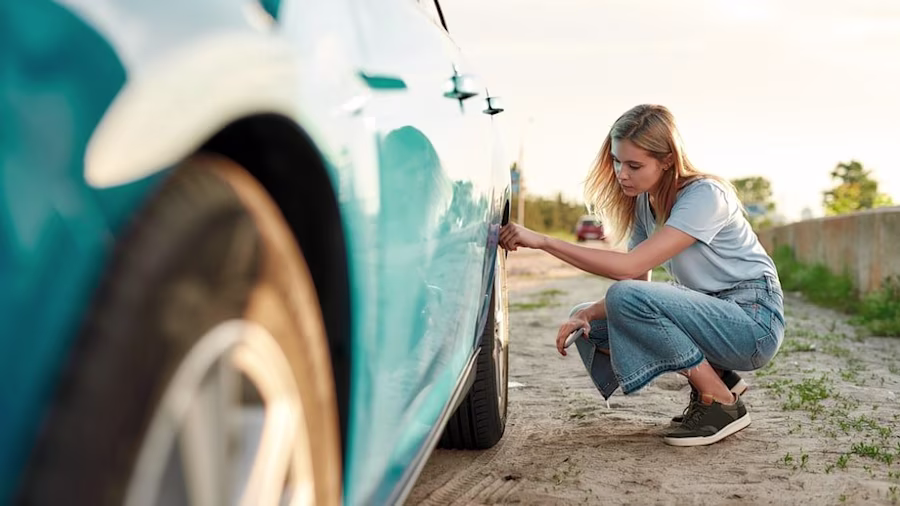 Woman checking car tyres