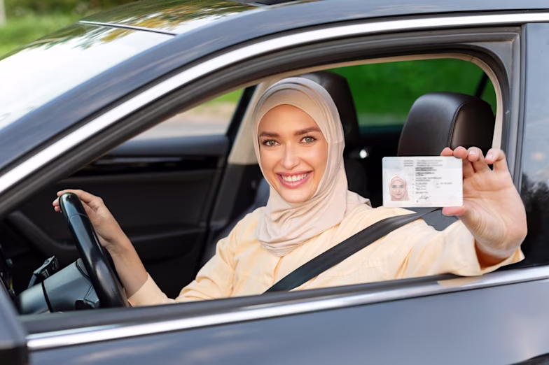 Woman in a hijab sitting in a car and holding her driving licence