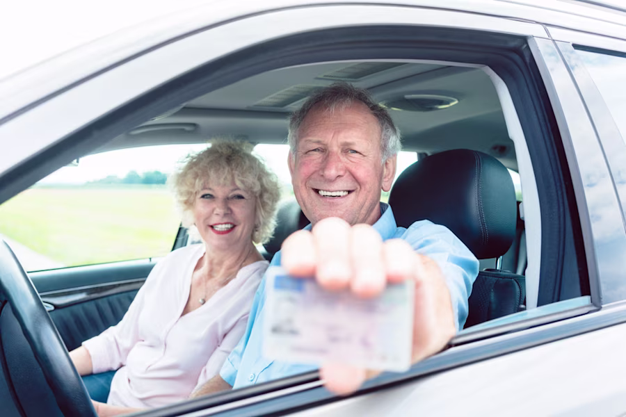 Older couple in car holding a driving licence