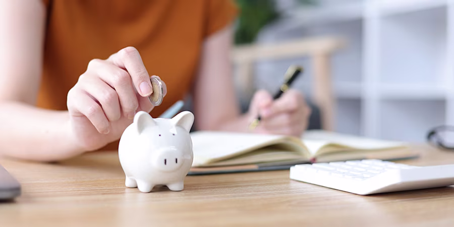 Woman adding coin to piggybank