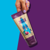 An image of a hand holding Aussie Conditioner on the puple-blue background