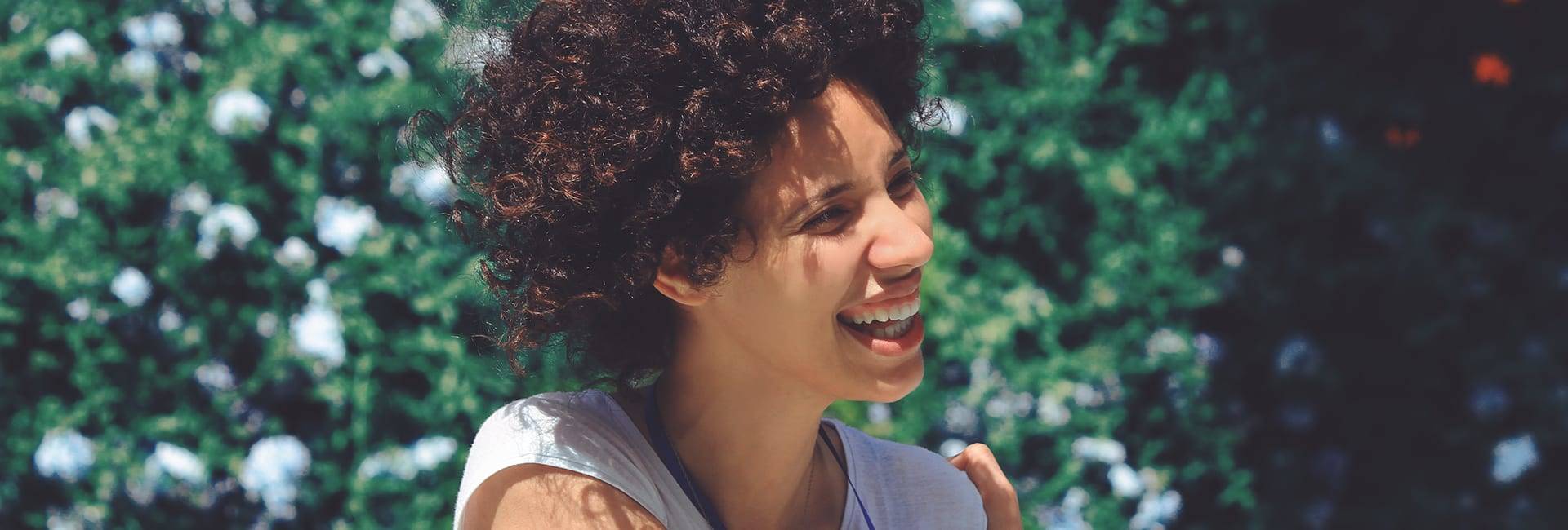 A filtered photo of a woman with short curly hair smiling and posing