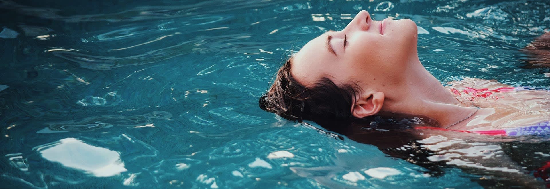A photo of woman lying on the swimming pool surface - a close up on her face