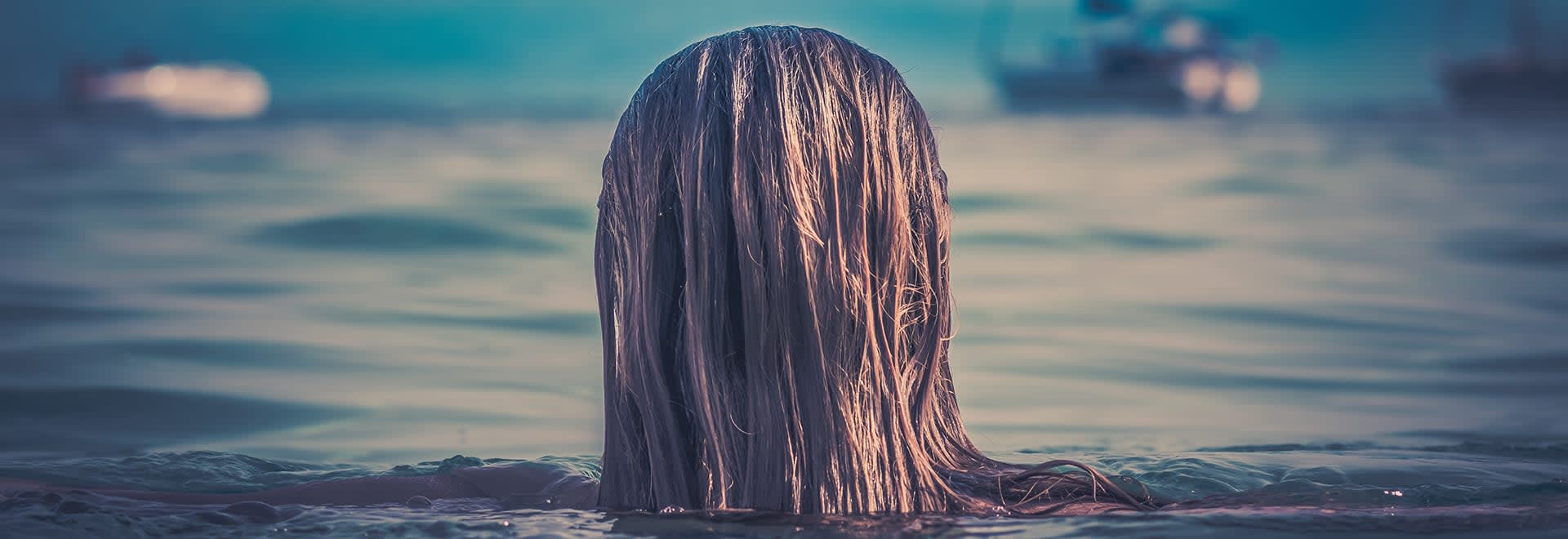 A close up photo of back of the head with wet hair diving in the water
