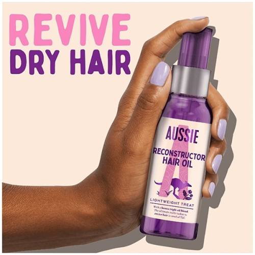 A picture of Reconstructor hair oil Bottle in hand with claim: revive dry hair.
