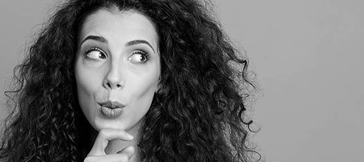 The black and white photo of a thoughtful young woman with long curly dark hair looking on the side