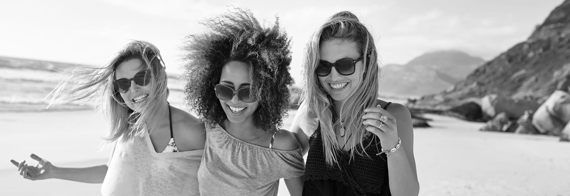 The black and white photo of 3 smiling women on the beach