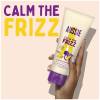 A picture of calm the frizz conditioner tube in hand and claim: calm the frizz.