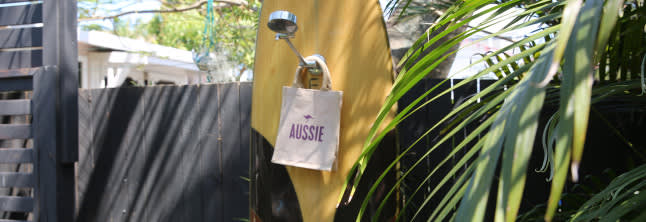 A photo of beach surroundings with Aussie bag on the wooden fence