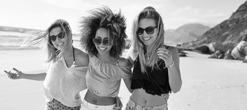 The black and white photo of 3 smiling women on the beach