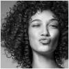 A black and white portrait of a woman with  curly hair.