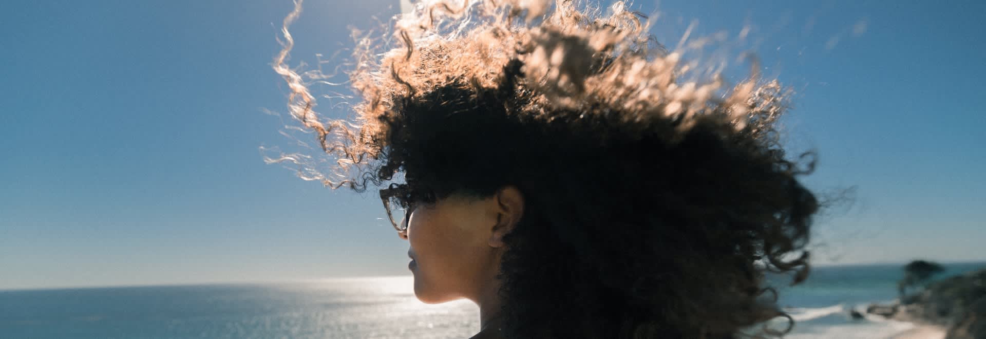 Picture of a woman with very curly hair staring at the ocean