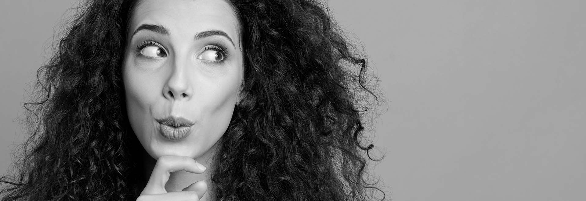 The black and white photo of a thoughtful young woman with long curly dark hair looking on the side