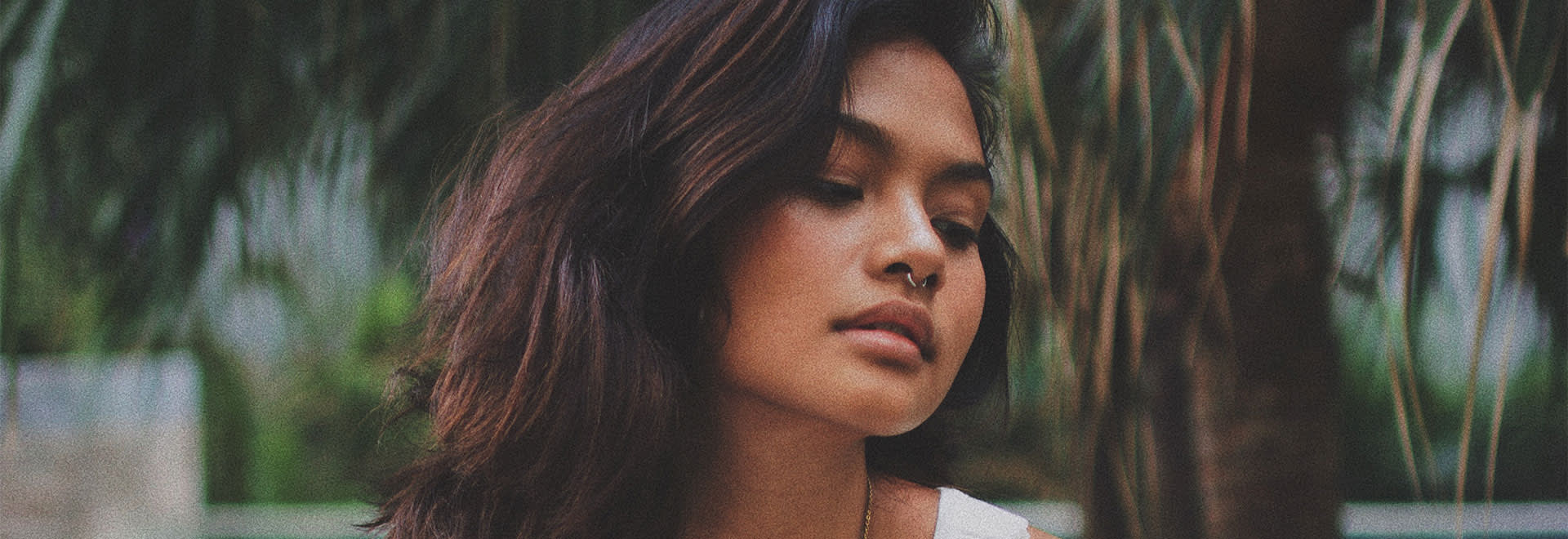 A styled photo of a woman with dark mid-lenght hair looking down on her side