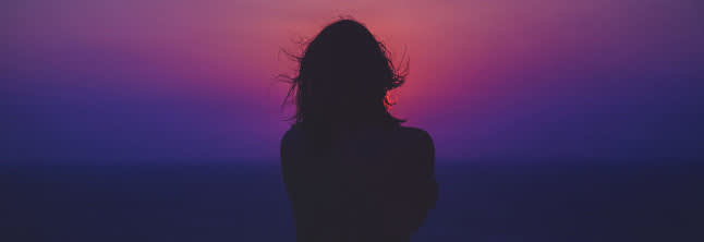 A woman's shape on the dark purple sunset background