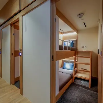 Interior view of a compact sleeping cabin with a single bed and neutral decor.