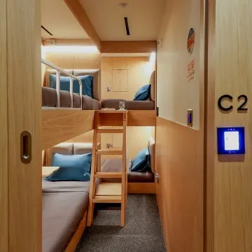 Interior view of a compact sleeping cabin with a single bed and neutral decor.