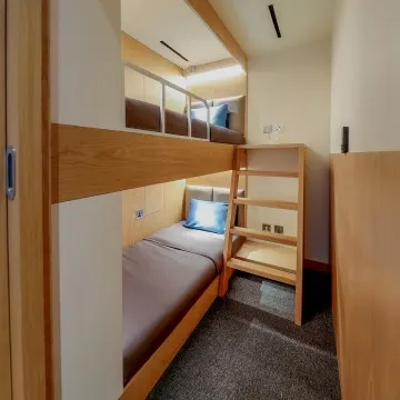 Interior view of a private sleeping cabin with bed and neutral-toned furnishings.
