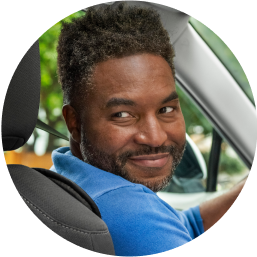 Richard, a Lyft driver, sits in the driver’s seat. He is looking behind his shoulder.