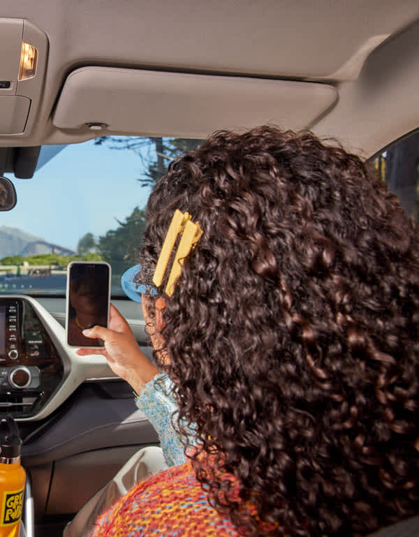 Woman on her phone in the front passenger side of a car. 