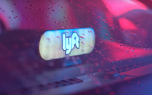 A Lyft Amp glowing behind a windshield with raindrops on it.
